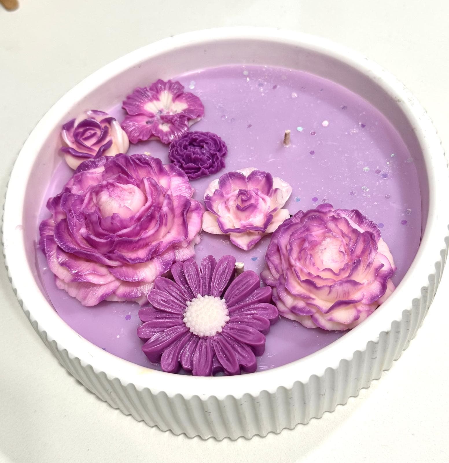 Vela decorativa floral en recipiente redondo